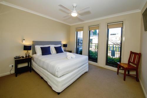a bedroom with a bed and a chair and windows at 39C Cypress in Mulwala