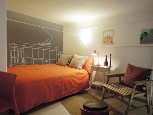 1 dormitorio con 1 cama de color naranja y 1 silla en V12 Design Apartments, en Milán