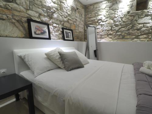 a bedroom with a white bed and a stone wall at Captain Emo City Apartments in Pula