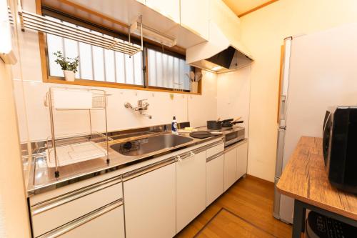 a kitchen with white cabinets and a sink at Skytree Tokyo House Takasago in Tokyo