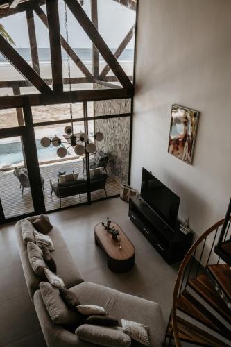 Una sala de estar con un sofá y un televisor. en Playa Laska - Oceanfront Luxury Villa with Pools, en Playa Venao