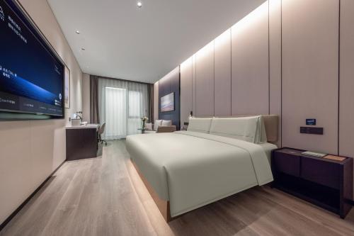 une chambre avec un grand lit blanc et une télévision dans l'établissement Atour Hotel Guangzhou Haizhu Taikoo Wharf-Free Shuttle Bus For Canton Fair-Self-service laundry 广州海珠太古仓亚朵酒店-广交会展期提供免费穿梭巴士, à Canton