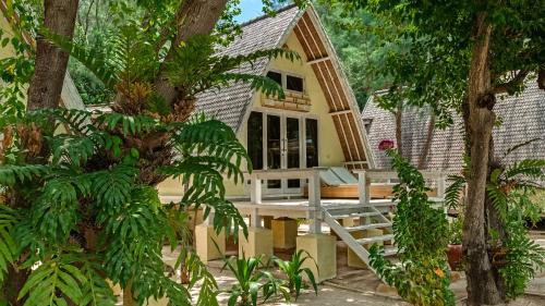 a small yellow house with a porch and trees at Pearl of Trawangan in Gili Trawangan