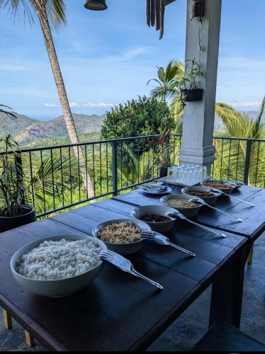 a table with bowls of food on top of a balcony at Sara's Grove Boutique Bungalow in Haputale