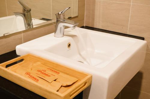 ein weißes Waschbecken in einem Badezimmer mit einem Holztablett in der Unterkunft TPHomes Vista in Ho-Chi-Minh-Stadt