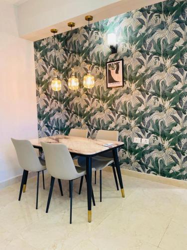 a dining room table and chairs with a tropical wallpaper at HomeyStays 2BHK Lakeside walk in Rāi