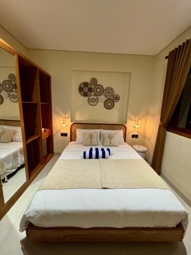 a bedroom with a large white bed with blue pillows at Casa Deva in Uluwatu