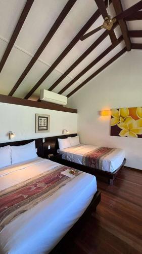 two beds in a room with a ceiling at Mana Island Resort & Spa - Fiji in Mana Island