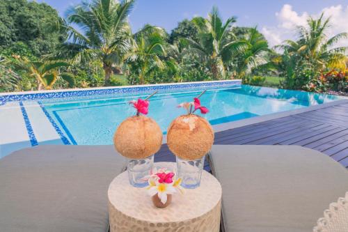 two glasses on a table next to a pool at Avaiki Nui Villa in Avarua