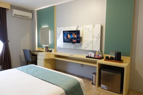 a hotel room with a bed and a desk with a television at Grand Kangen Hotel Urip Sumoharjo in Yogyakarta