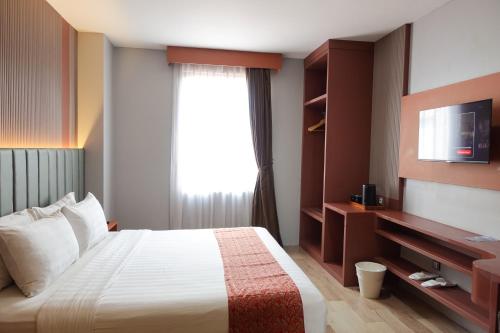 a hotel room with a bed and a window at Grand Kangen Hotel Urip Sumoharjo in Yogyakarta
