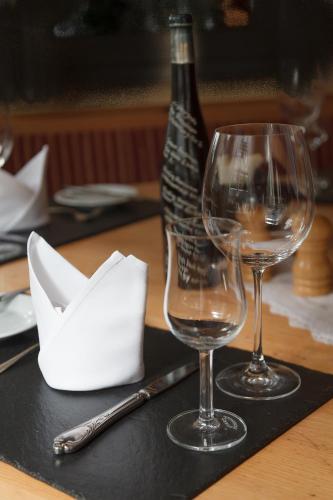 two wine glasses on a table with a bottle of wine at Hotel Restaurant Lindenhof in Bad Laasphe
