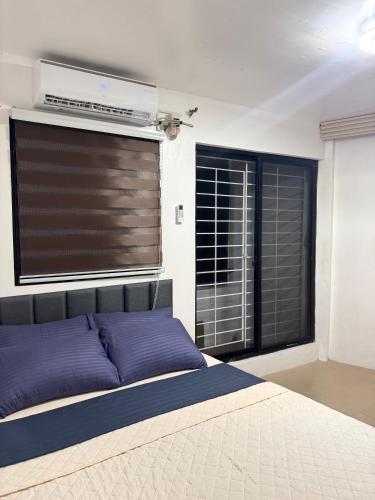 a bedroom with a bed with purple pillows and a window at Metro Naga Bnb 