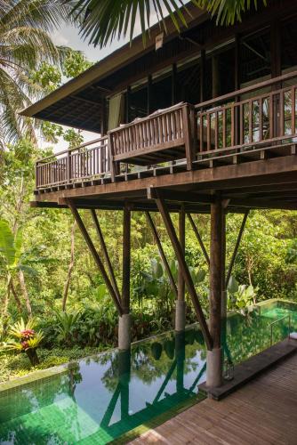 a house with a deck over a swimming pool at Komaneka at Bisma Ubud in Ubud