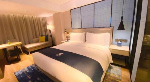 a hotel room with a large bed and a couch at Echarm Hotel Shenzhen World Exhibition and Convention Center in Shenzhen