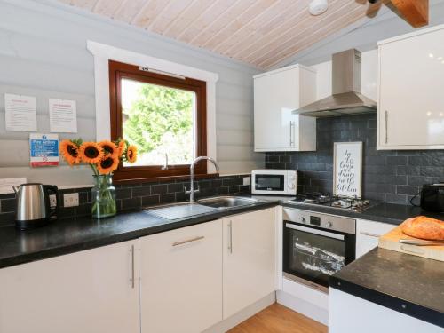 a kitchen with white cabinets and a vase of flowers at Sunny View in Rhayader