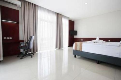 a bedroom with a bed and a chair and a window at Karlita Hotel Tegal in Tegal