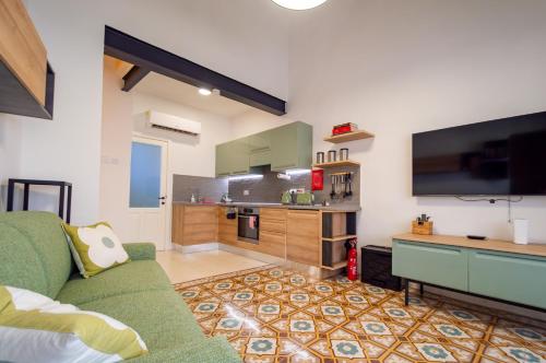 a living room with a green couch and a kitchen at 13, Mustard in Birgu