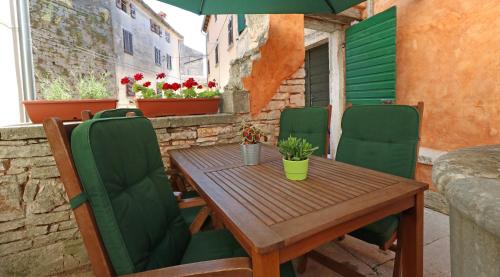 a wooden table with green chairs and an umbrella at Holiday Home Bale - Valle in Bale