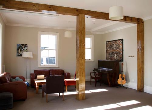 sala de estar con sofá y piano en Verandahs Parkside Lodge, en Auckland