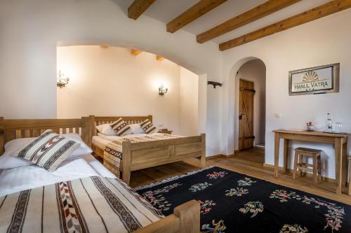 a bedroom with two beds and a table at Hanul Vatra in Horezu