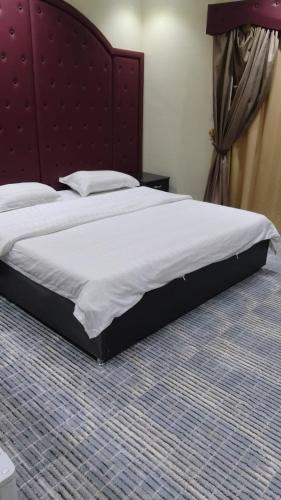 a large bed in a bedroom with a red headboard at عرعر Desert Rose Hotel in Arar