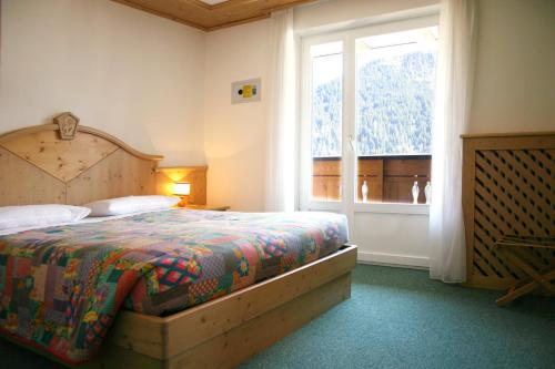 um quarto com uma cama e uma grande janela em Hotel Cima Dodici em Vigo di Fassa