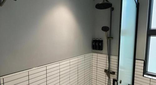 a bathroom with a shower and a tile wall at Harbour Bay Hotel in Hong Kong