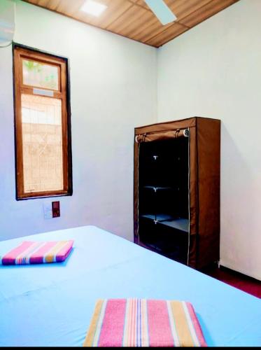 a bedroom with a bed and a cabinet and a window at Mango garden villa in Pottuvil
