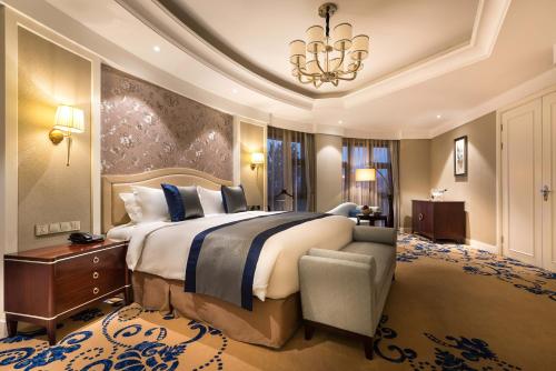 a large bedroom with a large bed and a chandelier at Pullman Tangshan in Tangshan