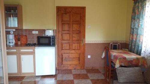 una cucina con porta in legno e tavolo e una cucina di Bodzavirág Apartman a Zalakaros