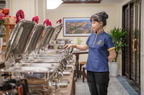 a woman standing in front of a row of pans at Le Pavillon Hoi An Paradise Hotel & Spa in Hoi An