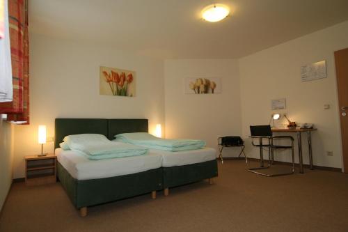 a bedroom with a bed and a table and a desk at Pension Kasper in Vienna