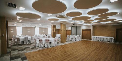 a banquet hall with white tables and white chairs at Hotel Radocza Park Business in Radocza