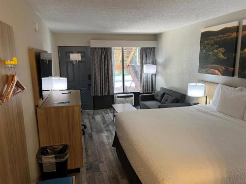 a hotel room with a large bed and a chair at Days Inn by Wyndham Branson Ozarks in Branson