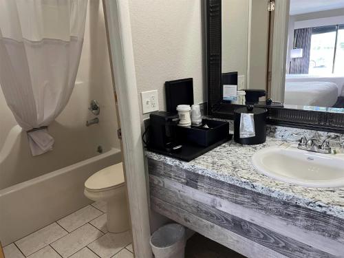 a bathroom with a sink and a toilet and a mirror at Days Inn by Wyndham Branson Ozarks in Branson