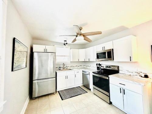 a kitchen with white cabinets and a ceiling fan at Renovated charming 2BR close to French Quarter in New Orleans