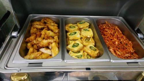 three metal trays of food in a refrigerator at Bacninh Charming Hotel in Bắc Ninh