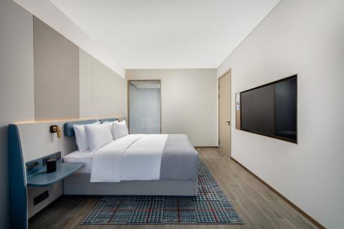 a hotel room with a bed and a flat screen tv at 乌鲁木齐高铁站农业大学万达悦华酒店 in Ürümqi