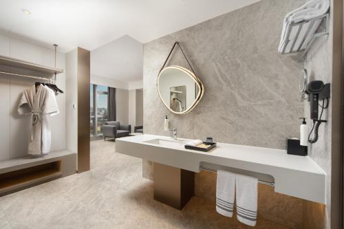 a bathroom with a sink and a mirror at 乌鲁木齐高铁站农业大学万达悦华酒店 in Ürümqi