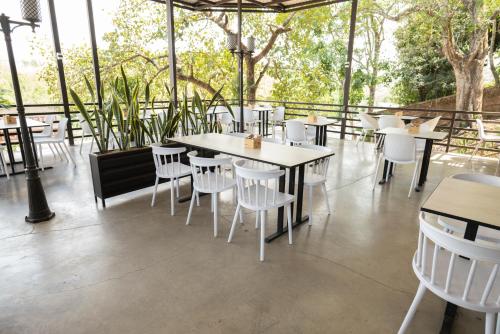 a restaurant with white tables and chairs and trees at Hotel Jardin De Las Marias in Suchitoto
