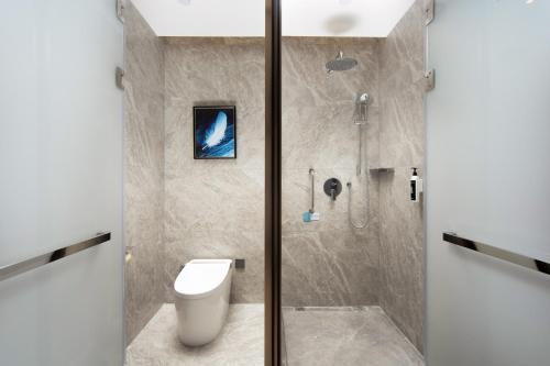 a bathroom with a toilet and a shower at 乌鲁木齐高铁站农业大学万达悦华酒店 in Ürümqi