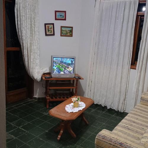 a living room with a tv and a table at Casa com piscina para até 6 pessoas com duas camas de casal e sofá-cama casal in Serra Negra