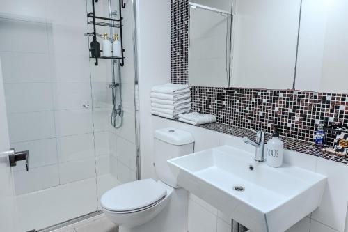 a white bathroom with a toilet and a sink at City Living, Prime Location with Parking & Amenities in Melbourne