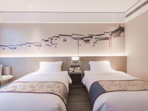 two beds in a hotel room with a painting on the wall at GRACE Select Hotel (Kunshan Huaqiao International Convention Center) in Suzhou