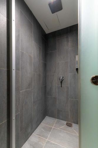 a bathroom with a shower with gray tiles at T+ Hotel Butterworth in Butterworth