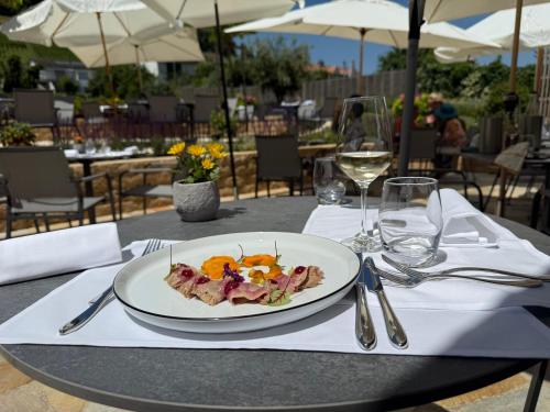 a plate of food on a table with wine glasses at Hotel Restaurant Croix Blanche in Sugiez