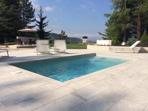 a swimming pool with two chairs and a table at Hotel Nido dell'Aquila in Assergi