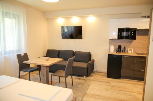 un salon avec un canapé et une table et une cuisine dans l'établissement AKZ Apartman, à Makó