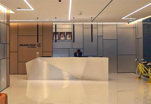 a person sitting at a reception desk in a building at Golden Tulip Sharjah in Sharjah
